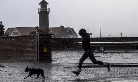 A woman runs with her dog past the Memmertfeuer lighthouse in Juist, Germany