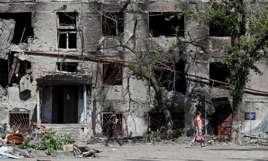 People walk past a residential building heavily damaged during Ukraine-Russia conflict in the southern port city of Mariupol, Ukraine May 30, 2022.