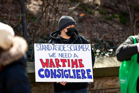 a person holds a sign that reads ‘stand aside Schumer we need a wartime consigliere’