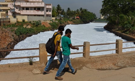 Pedestrians cover their noses as they cross a bridge over a frothing canal, which once carried water from Bellandur Lake to Varthur Lake, in east Bangalore in 2015.