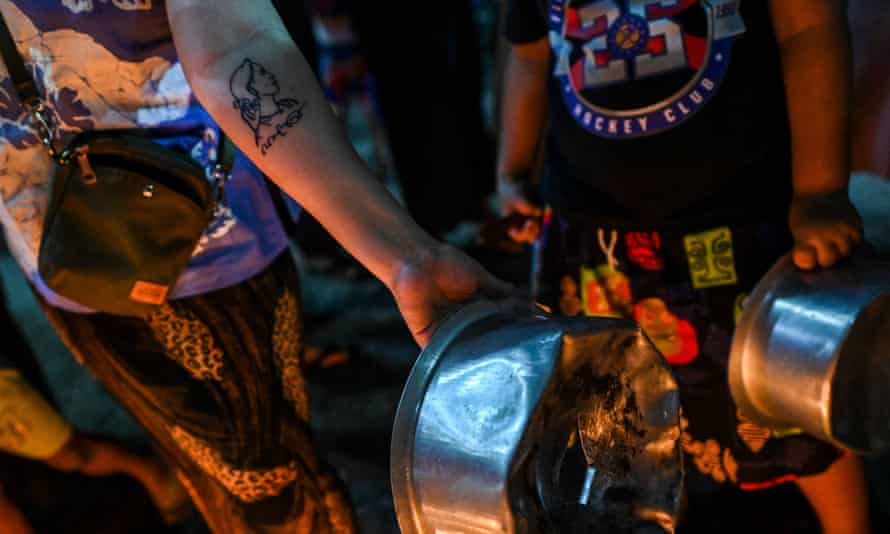 A woman displays a tattoo of Aung San Suu Kyi on her hand as she bangs pots and pans in opposition to the military coup.