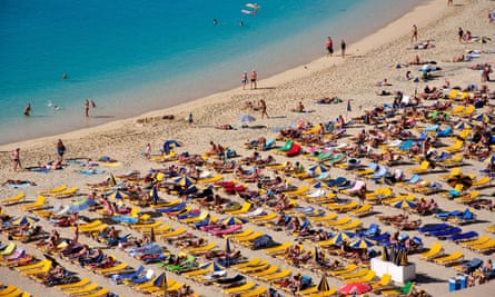 Rows of people lying on a beach.