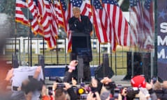 a man speaks in front of American flags