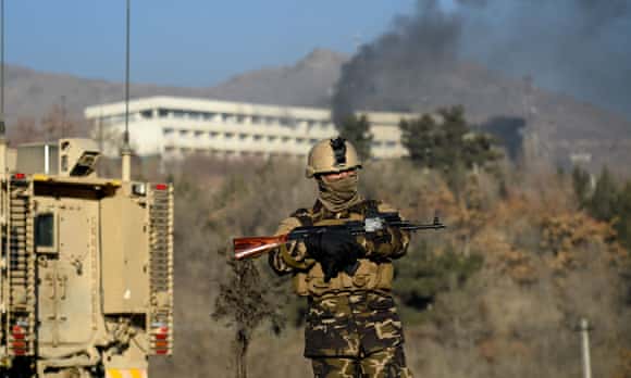An Afghan soldier stands guard as smoke billows from the Intercontinental Hotel in Kabul.