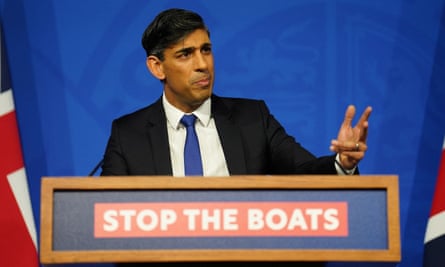 Rishi Sunak standing at a podium with a ‘Stop the boats’ logo