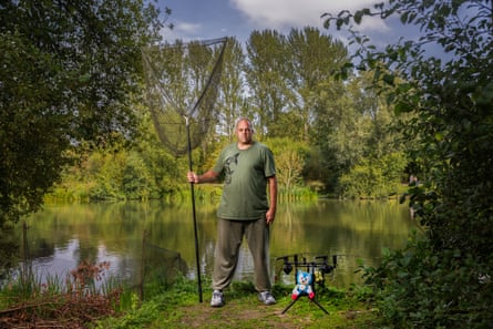 A man standing by a lake holding a very large fishing net
