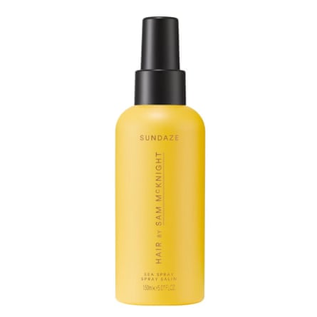 A bottle of sea spray for hair by Sam McKnight. It is a yellow bottle with a black cap and text. It is on a white background