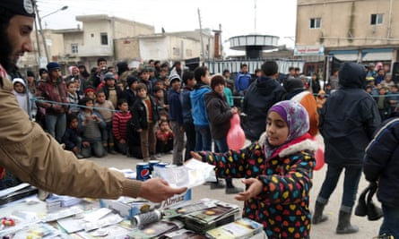 An Isis fighter distributes soft drinks, biscuits and religious pamphlets to local people in Tel Abyad, northern Syria