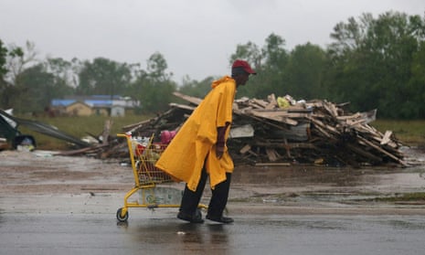 A man carries a shopping cart with supplies past a pile of debris collected after Hurricane Laura as Hurricane Delta approaches in Lake Charles, Louisiana, on Friday.
