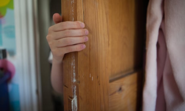Child's hand opening a scratched wooden door