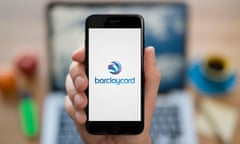 A man looks at his iPhone which displays the Barclaycard logo