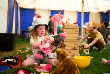 A young girl plays with a soft toy while sitting on the grass