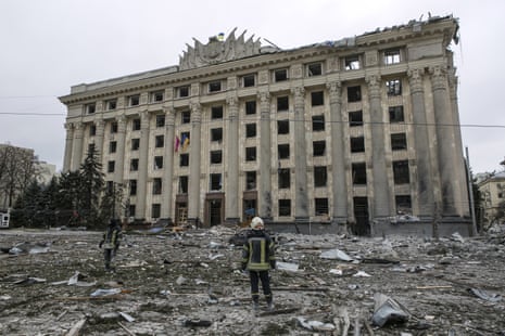 A member of the Ukrainian emergency services looks at the City Hall building in the central square after shelling in Kharkiv