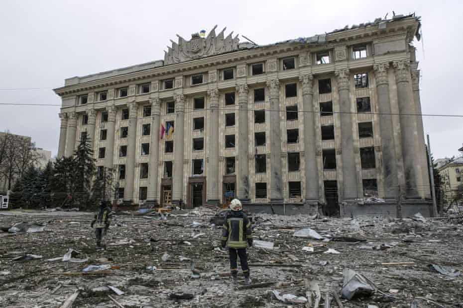A member of the Ukrainian emergency services looks at the City Hall building in the central square after shelling in Kharkiv
