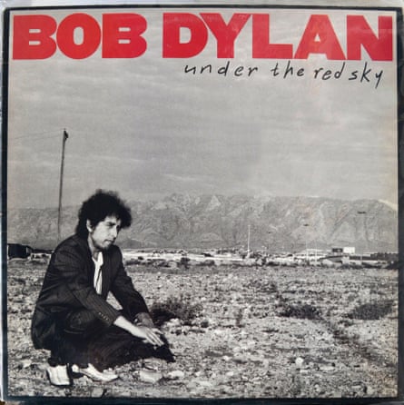 Bob Dylan in a suit crouched in the middle of nowhere with the text Under the Red Sky.
