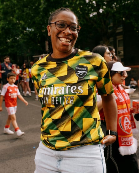 A woman wearing a green, yellow and black Jamaican influenced Arsenal top