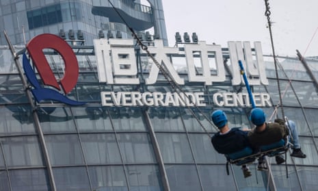 People ride on a swing in the amusement park in front of the Evergrande Center building in Shanghai