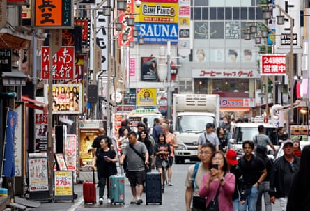 Tourists walk through the Shinjuku entertainment district in Tokyo.