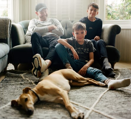 Mark Edmondson, who is living with cancer, sitting on a sofa with one son; the other son and a dog on the floor in front of them