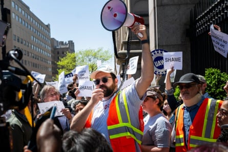 a man holds a megaphone high in the air in front of a crowd of people