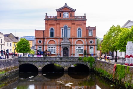 A red-brick town hall building on a bridge over a river