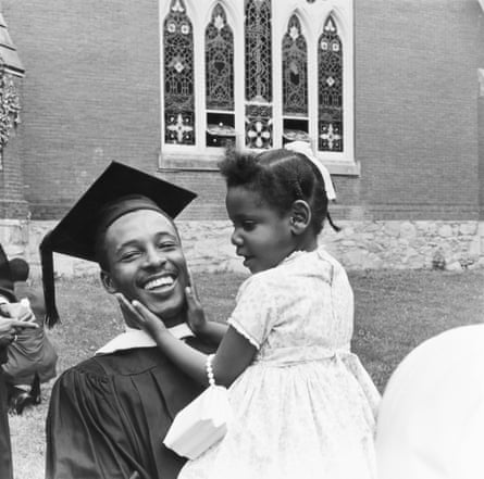 Man smiling while little girl in his arm holds his cheeks