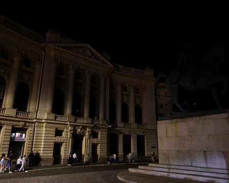 Tourists walk past the Central University Library Carol I that has its architectural outdoor lighting turned off, in Bucharest, Romania.
