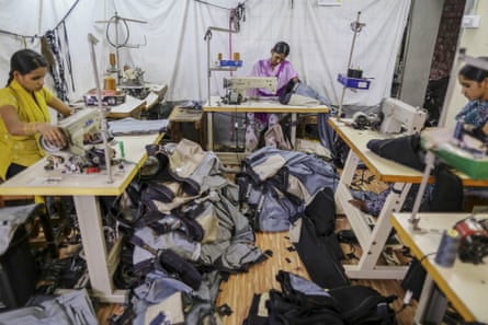 Workers operate sewing machines inside a jeans factory in Karnataka.