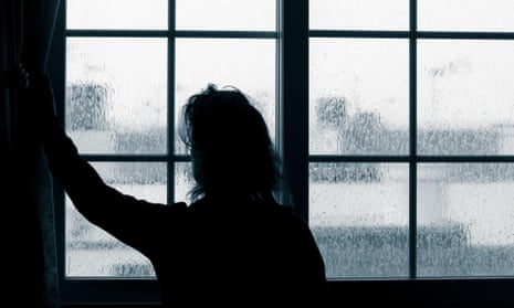 Woman looks out window on rainy day.