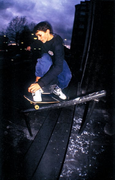 A person skateboarding down a railing with a purply grey sky in the background