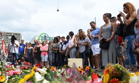 People stand next to flowers laid for the victims of the shooting