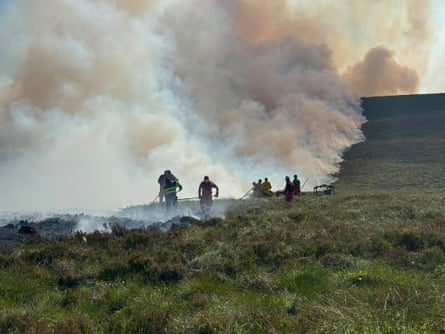 Firefighters standing by a column of smoke.