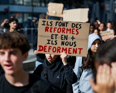A person holds a placard reading: "They make reforms, and on top of that, they deform us.", as high school students take part in a spontaneous street protest in Liège, Belgium.