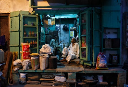 A shopkeeper and his sales assistant wait for customers inside a family-owned kirana in an alley in the old quarters of Delhi
