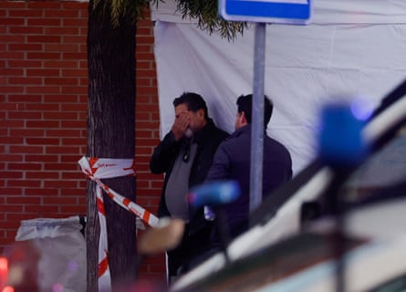 A man covers his face, as he is crying outside an emergency centre, while another man stands next to him