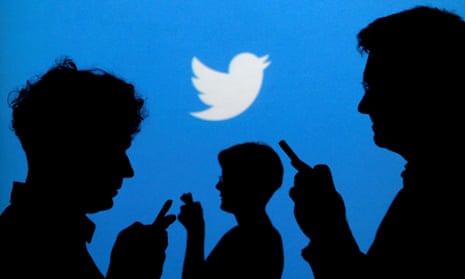 Silhouette of people using phones in front of Twitter  backdrop