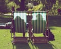 Two people sit in striped deckchairs on grass in a sunny St James Park in London