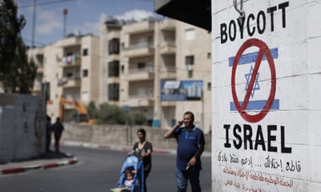 Palestinians walk past a sign painted on a wall in the West Bank town of Bethlehem.