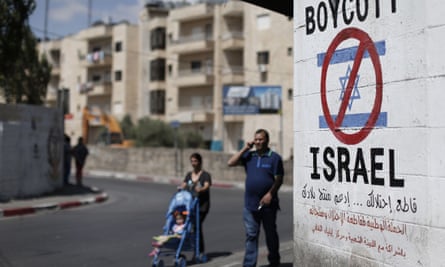 Palestinians walk past a sign painted on a wall in Bethlehem last year calling for a boycott of Israeli product