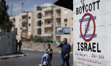 Palestinians walk past a sign on a wall in Bethlehem