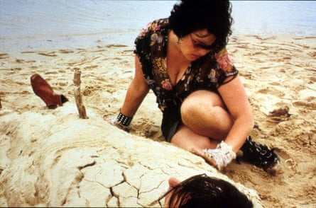 Sweetie (Genevieve Lemon) sits next o her sister Kay (Karen Colston), whom she has buried in the sand on the beach, in a scene from Sweetie