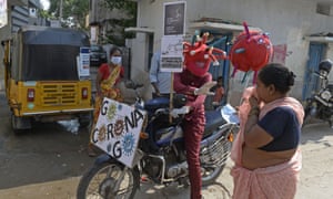 An employee of a private hospital wearing headgear themed on Covid-19 coronavirus rides his motorbike around counselling people at markets and slums about the precautionary measures to be taken against the spread of the coronavirus in Hyderabad on May 31, 2021. (Photo by Noah SEELAM / AFP) (Photo by NOAH SEELAM/AFP via Getty Images)