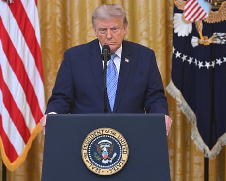 a man in a suit stands at a lectern