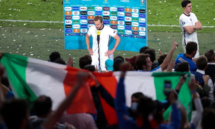 Harry Kane speaks to the media infront of celebrating Italian fans.