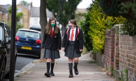 Two girls in face masks walk to school