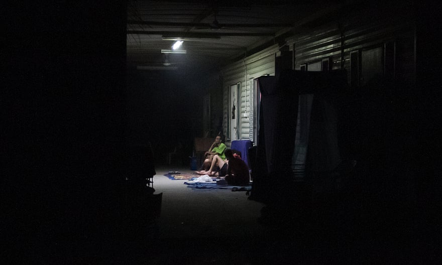 Refugees sit under a battery-powered light.