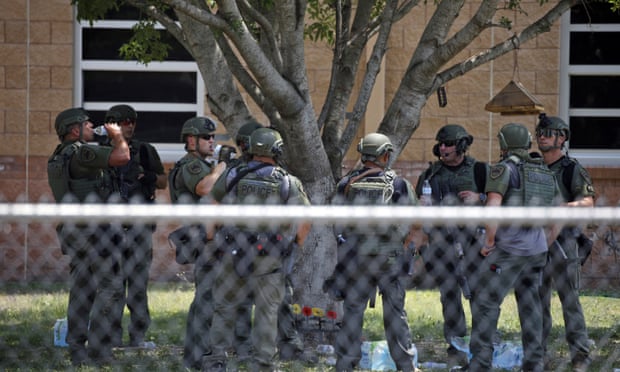 Law enforcement personnel stand outside Robb elementary school after the mass shooting, on 24 May in Uvalde, Texas. 