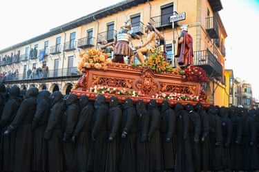 Image 21: Figures in black hoods and robes carry an ornate coffin