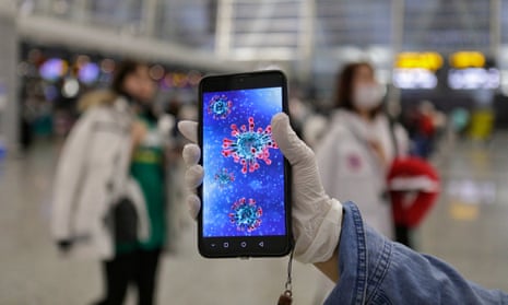 A passenger shows an illustration of the coronavirus on his phone at Guangzhou airport in China