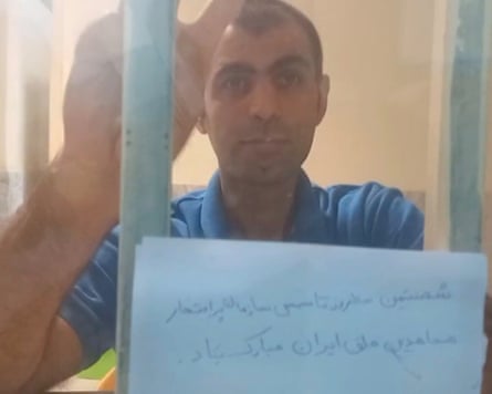 Babak Alipour holding up a paper to his cell railings